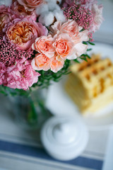 Delicate bouquet of eustomas, carnations, cotton, spray roses and roses David Austin, in pink and beige colors on a background of plates with waffles - 318668636