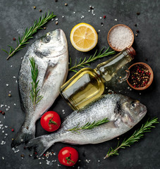 Fresh dorado fish with spices and ingredients tomato, razmorin, sunflower oil, lemon for cooking on a stone background