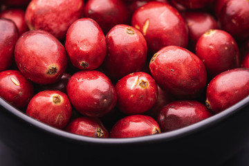 Close up of ripe red cranberries in a black bowl