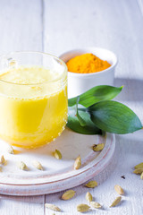 Cup with golden latte, turmeric and cardamom on white background