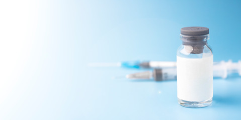 Medical glass bottle with copy space, on a blue background with syringes. Selective focus. Medical...