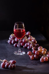 A glass of red fruit wine. Close-up of grape vine on a dark background in low key. Copy space. Banner for cafe, winery and restaurant.