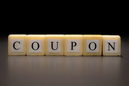 The word COUPON written on wooden cubes isolated on a black background...