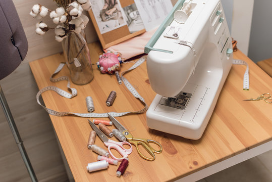 The workplace of a seamstress. Sewing machine on the table, thread, scissors and mannequin