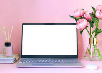 Female work space with a laptop, a peony flower bouquet on the pink background. Copy space. Mock up