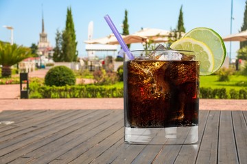Cola with ice cubes in a glass on wooden desk