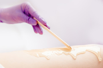 Shugaring hair removal concept. Process depilation of legs girl with sugar paste in spa salon, white background