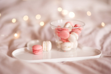 Tasty macaroon cookies on white plate  in glass bottle over glowing lights closeup. Good morning.