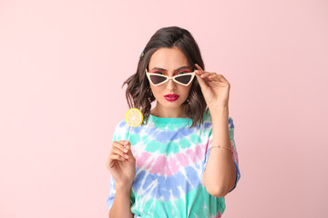 Beautiful young woman with lollipop on color background
