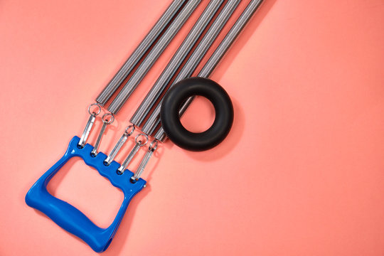Espander spring with blue handle on pink background