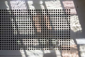 Powdered metal ventilation grille - with shadows forming a regular pattern on the background