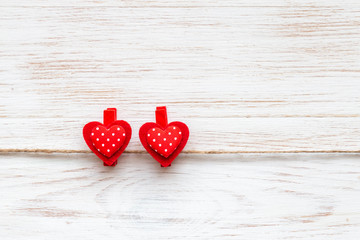 Two red polka-dot hearts on clothespins over wood border. Valentines day background