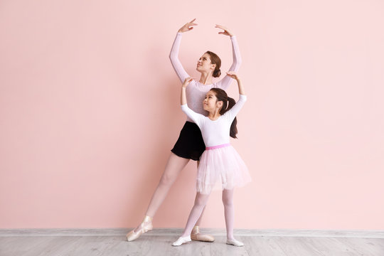 Little ballerina training with coach against color background