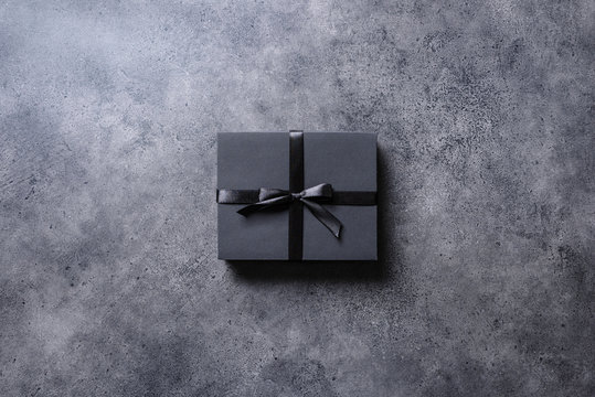 Black Gift Box With Black Ribbon Over Concrete Desktop. Top View.