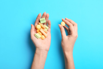 Female hands with chewing gums on color background