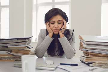 Woman brunette businesswoman in glasses with a mountain of documents on the table tired depressed...
