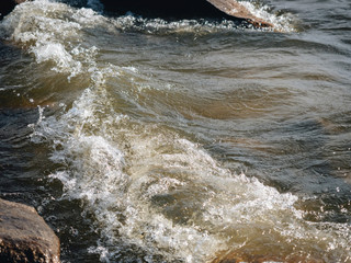Waves breaking on stones on the lake shore with a splash and fast motion