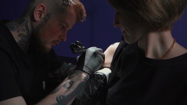 Footage of man doing tattoo of snake in studio