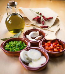  Fresh ingredients for cold tomato soup, tomatoes, peppers, onion, garlic, olive oil. On a wooden table and clay utensils