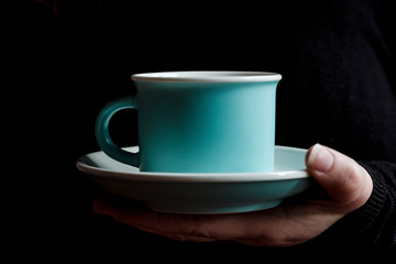 blue cup of coffee held by woman's hand