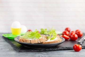 Sandwiches with soft cheese, lettuce and tomatoes on grain bread.