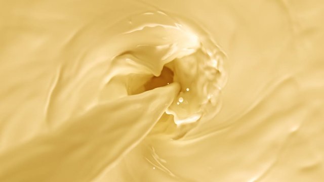Super Slow Motion Shot of Pouring Yellow Milk into Wortex at 1000fps.