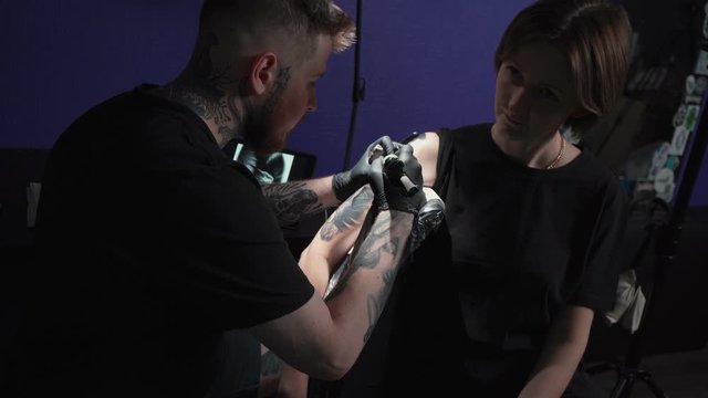 Shooting of man doing tattoo of snake for woman in studio
