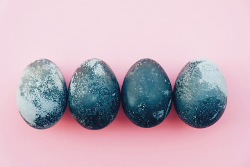 Natural dyed blue colored eggs on pastel pink background.