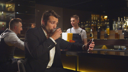 Man drinks alcohol at the bar and talks by video link on the phone 