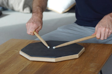 man holding two drum sticks and drumming on a practice pad © Thomas