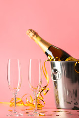 Bucket with bottle of champagne and glasses on color background