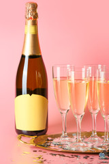 Glasses and bottle of tasty champagne on color background