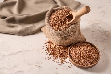 Bowl and bag with raw buckwheat on table