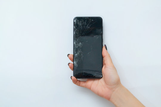 Female Hand Holds A Broken Mobile Phone On A White Background, Close-up