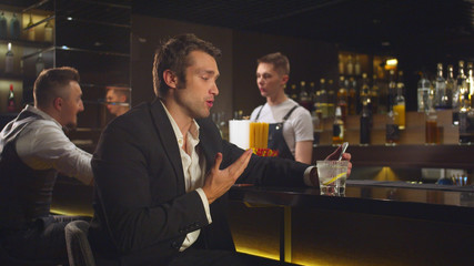 Man sits at the bar and talks by video link on the phone