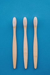 Stylish natural eco friendly toothbrushes with wooden bamboo handle on blue background.