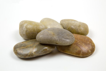 Fototapeta na wymiar Sea semicircular polished stones of gray brown yellow color folded in a certain figure, isolated on a white background.
