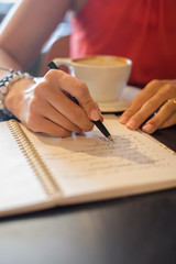 Fototapeta na wymiar Woman writing in notebook at coffeeshop