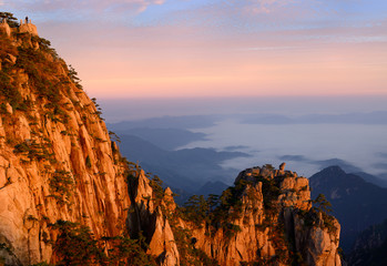 Lion Peak and Stone Monkey watching the Sea Peak at first light with fog in valley at Huangshan Mountains China
