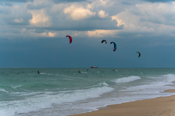 Several kite-surfers  fighting with gusty windy weather and waves in the ocean. Amazing adventure and adrenaline sport. Modern and active life style. 