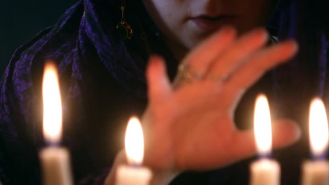 Witch telling spell from old book under candles. Fortune teller call spirits. Halloween concept. Mystical video 4k. Occult and esoteric atmosphere 