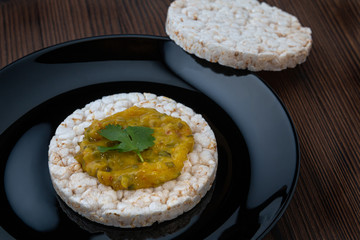 Rice cakes with vegetables sauce on a black plate on a wooden table