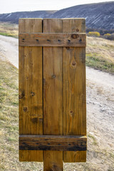 Wooden shield mounted next to a mountain country road.
