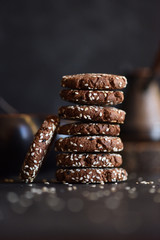 Healthy vegan snack. Gluten free chocolate sesam seed cookies in pile on black background side view