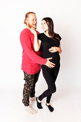 Caucasian man with a beard in a red sweater hugs a pregnant Caucasian girl