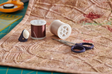 Sewing accessories lying on a reverse side of a quilt, cutting mat, ruler, rotary cutter