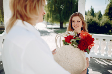 Elegant mother with young daughter. Family in a park. Women with a bouquet of flowers