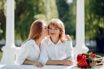 Elegant mother with young daughter. Family in a park. Women with a bouquet of flowers