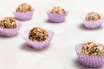 Healthy raw natural candies made of dried fruits, nuts and various seeds on neutral grey background