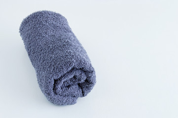 Gray terry towel folded into a roll on a white background.